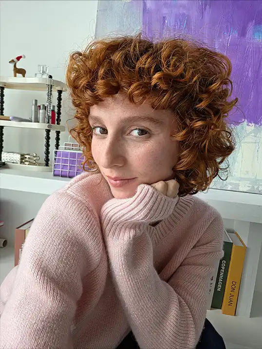 Göndör hajú nő szelfit készít beltérben a Galaxy S26 Ultra telefonnal.